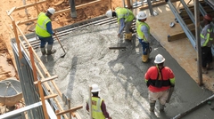Workers leveling concrete on multi-story construction