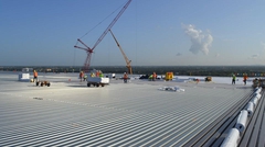 Cranes and workers installing steel deck on the stadium roof
