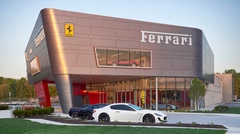 Two-story Ferrari car dealership exterior with exotic cars in showroom and in parking lot