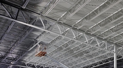 Close-up of warehouse ceiling being painted. Workers on lift.