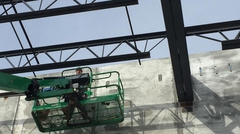 Worker on lift installing steel joists on steel girders
